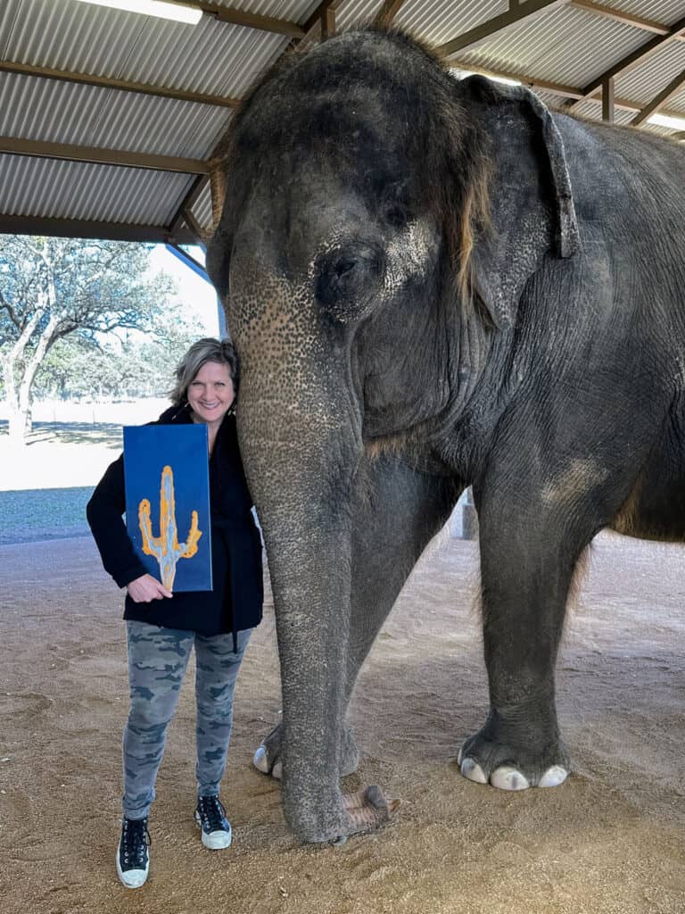 lynn poses with painting made by elephant